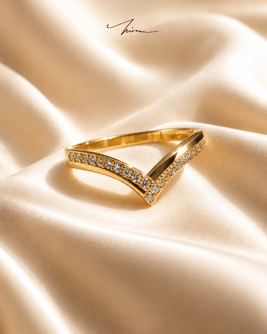 Cincin emas berbentuk V bertatah berlian di atas sutra krem