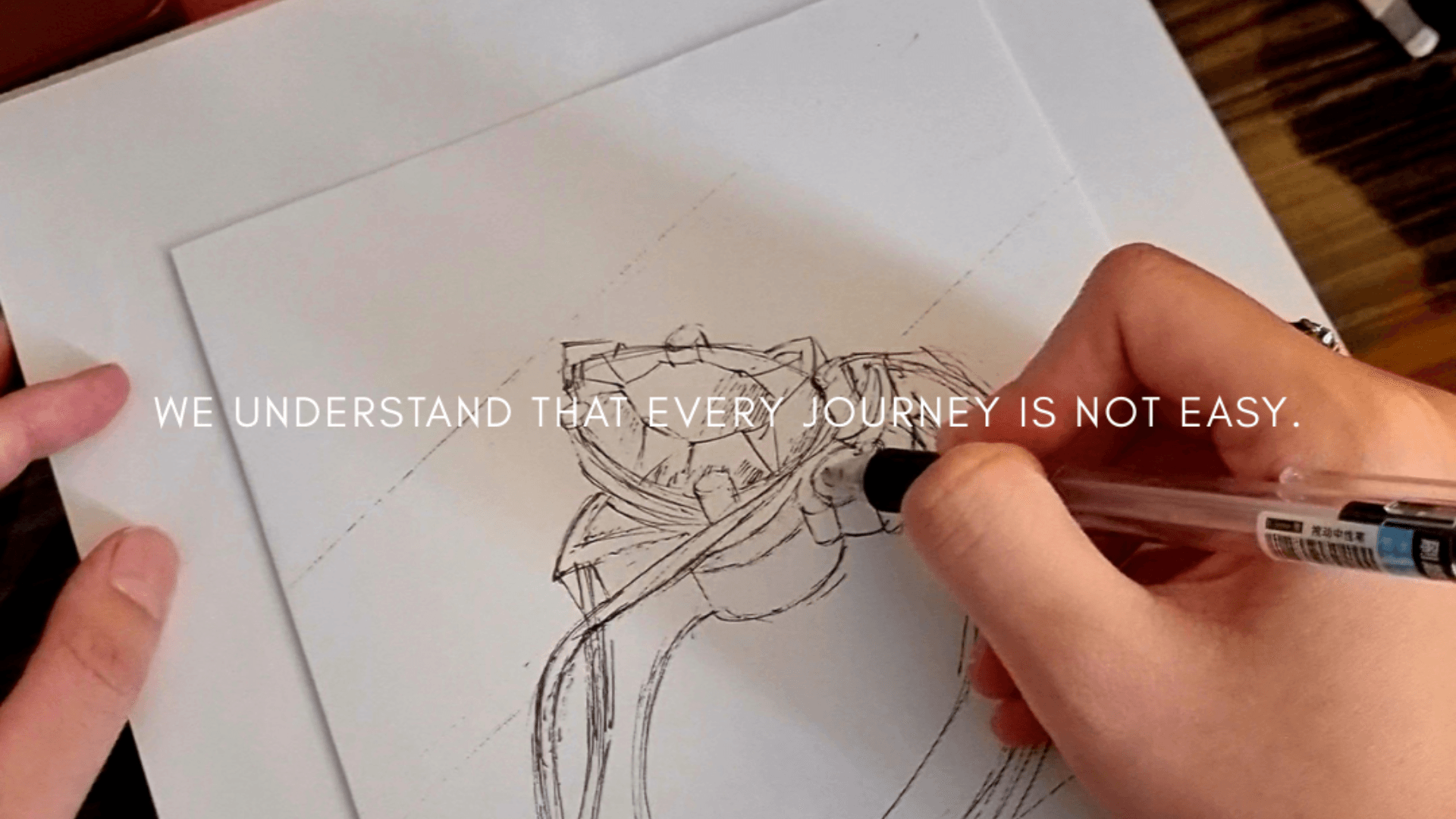 A hand sketching a ring design in the Kirana atelier notebook.