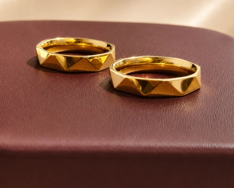 Sepasang cincin pernikahan emas bertekstur piramida di atas kulit marun
